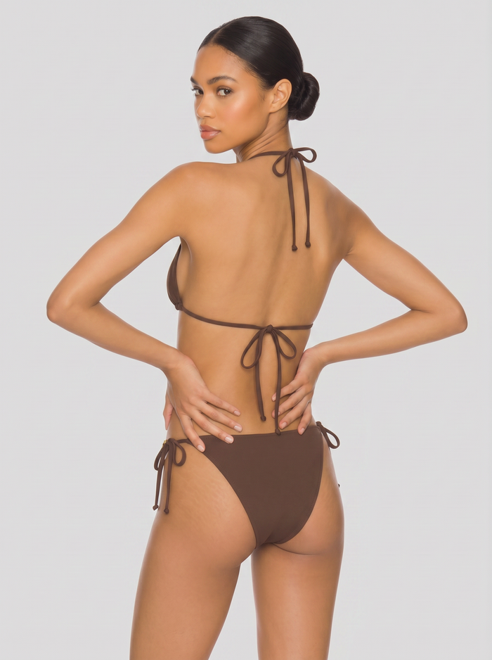Back view of brown tie-side bikini with halter and back ties on a model posing against a light studio background
